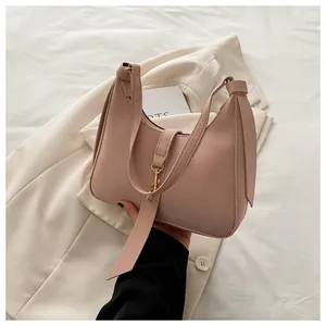 Close-up of pink matte leather underarm bag with gold buckle and adjustable strap