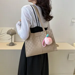 Vintage beige checkered tote bag with fashion label and peach plush charm on model