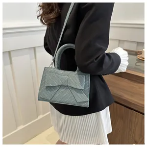 Detail of light blue bow handbag with woven texture and adjustable shoulder strap