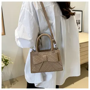 Detail of cream woven handbag with oversized bow accent and silver metal hardware
