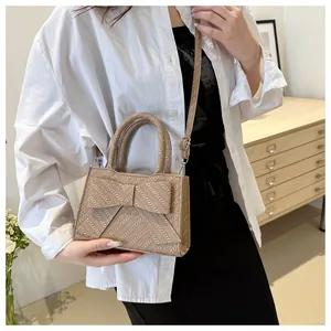 Detail of khaki crossbody bag with bow decoration and herringbone woven texture