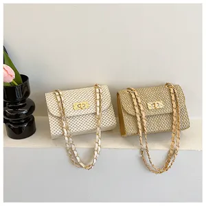 Detail of straw woven crossbody bags with gold chain straps and metal twist lock closures