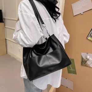 Minimalist black large capacity leather tote bag with chain strap and dual front pockets