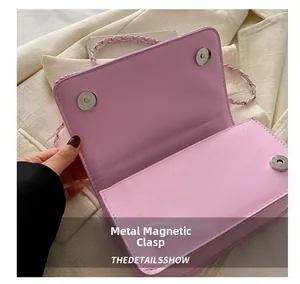 Détail des fermoirs magnétiques argentés et de la bandoulière tressée du sac violet