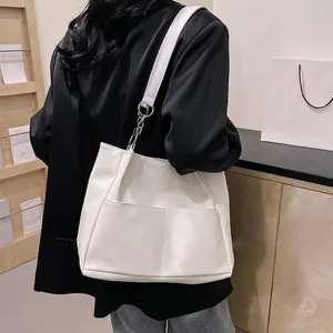 Minimalist white tote bag in soft leather with metal chain strap on female model