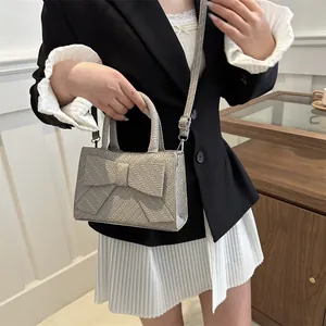 Chic beige woven handbag with large bow detail and adjustable crossbody shoulder strap