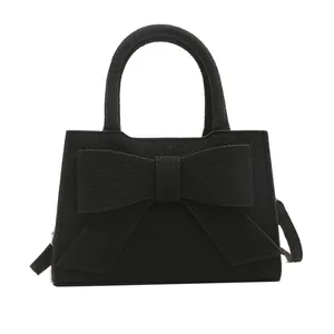 Black handbag featuring a large bow and herringbone texture with top handles and strap