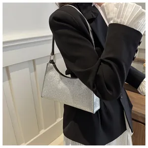 Dettaglio di una borsa a tracolla argento glitterata abbinata a un blazer nero