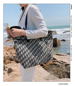 Détail du sac cabas jacquard avec poignée en cuir noir et pendentif doré en forme de R