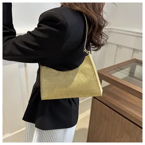 Vista laterale di una borsa sottobraccio con paillettes dorate su un modello elegante