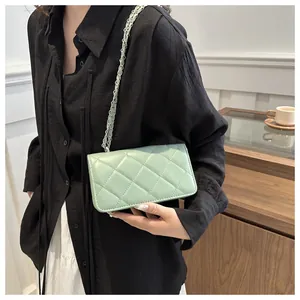 Détail d'un sac bandoulière matelassé vert menthe avec chaîne porté par un modèle