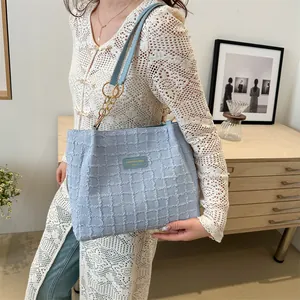 Borsa tote celeste testurizzata con spalline a catena dorata indossata da una modella