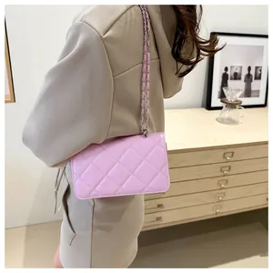 Détail d'un sac à bandoulière matelassé rose avec chaîne en argent porté par un mannequin