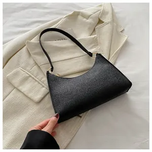 Dettaglio della borsa a spalla nera glitterata con zip dorata su un blazer bianco