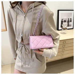 Gros plan détaillé d'un sac à bandoulière matelassé rose tenu par un mannequin en tenue chic