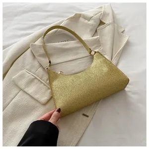 Dettaglio della borsa a spalla con paillettes oro champagne su sfondo di lenzuola