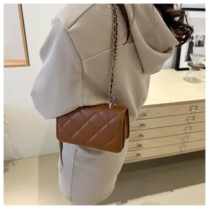 Détail du cuir matelassé marron et de la bandoulière en chaîne argentée du sac