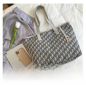 Détail du sac cabas en toile monogramme grise avec un charm lettre R en métal doré