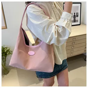 Detailed view of pink soft leather hobo bag with embossed logo on stylish model