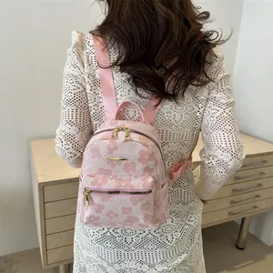 Pink mini backpack with floral embroidery shown on model wearing white crochet dress