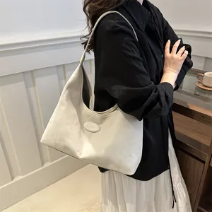 Cream white minimalist faux leather hobo tote bag for women shown as a shoulder carry