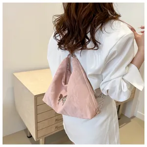 Détail du sac à dos rose plissé avec emblème papillon et bandoulière chaîne argent