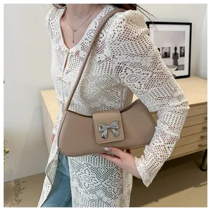 Dettaglio di una borsa a mezzaluna beige con fibbia a fiocco argento su pizzo bianco
