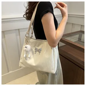 Detail van de gebroken witte geplooide draagtas met zilveren vlinder en pluche hanger