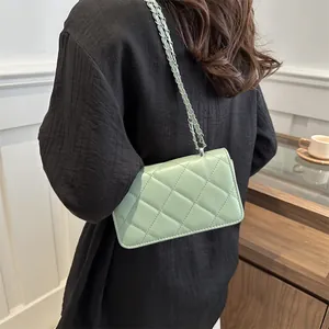 Sac bandoulière matelassé vert pâle avec chaîne argentée porté par un mannequin en intérieur