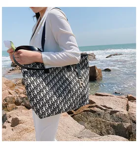 Gros plan du sac cabas en toile avec motif monogramme rétro et breloque en métal doré