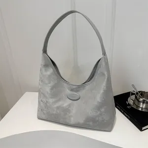 Detailansicht der grauen Hobo-Tasche mit Marmorstruktur und Logo auf einem Podest