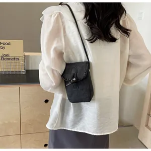 Detailed view of grey denim crossbody phone bag with stylish toggle button closure