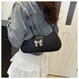 Dettaglio borsa a mezzaluna in pelle nera con fiocco argento indossata con giacca jeans