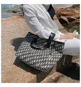 Détail du sac cabas à monogramme noir et blanc avec poignées en cuir et breloque dorée