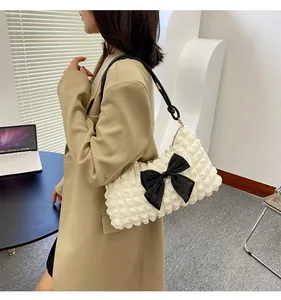 Close-up of cream puffy cloud shoulder bag with 3D bubble texture and black bow detail
