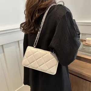 Sac à bandoulière matelassé crème avec bandoulière chaîne porté par un mannequin