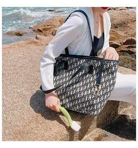 Détail du sac cabas en toile à motif de lettres avec pendentif en métal au bord de mer