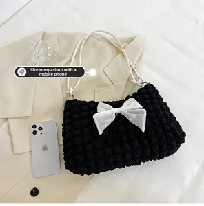 Detailed view of cloud puff bag with oversized organza bow and phone size comparison