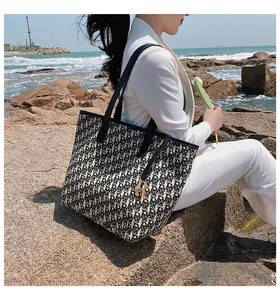 Gros plan détaillé d'un sac cabas en toile avec motif jacquard et pendentif doré R