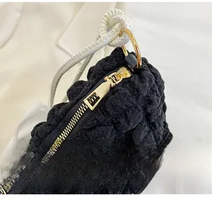 Detail of light gold zipper and white rope handle on black cloud bubble textured bag
