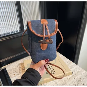 Close-up of vintage denim mini crossbody bag with leather trim and horn buckle detail