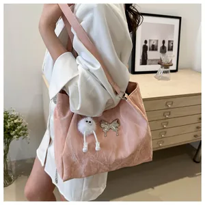Detail van roze draagtas met metalen vlinder en pluche popbedeltje over de schouder
