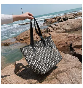 Détail d'un sac cabas en toile avec broderie monogramme noir et blanc au bord de mer
