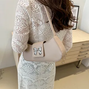 Elegante borsa a mezzaluna beige con fiocco in metallo argento in un ambiente lifestyle
