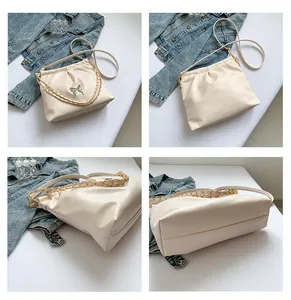 Detail view of cream white pleated crossbody bag with silver butterfly pendant decoration