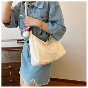 Detail of hobo shoulder bag in ivory with soft texture and cute plush charm