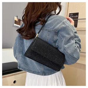 Close-up of a black sequin shoulder bag on a model showing sparkling glitter texture