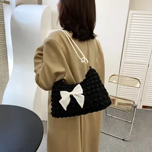 Detail of black cloud puff bag with white satin bow and thick rope shoulder strap