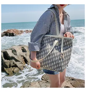 Détail du sac cabas en toile avec imprimé monogramme bleu et pendentif R doré au bord