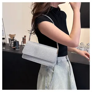 Silver glitter shoulder bag for women shown as an underarm clutch in a lifestyle setting
